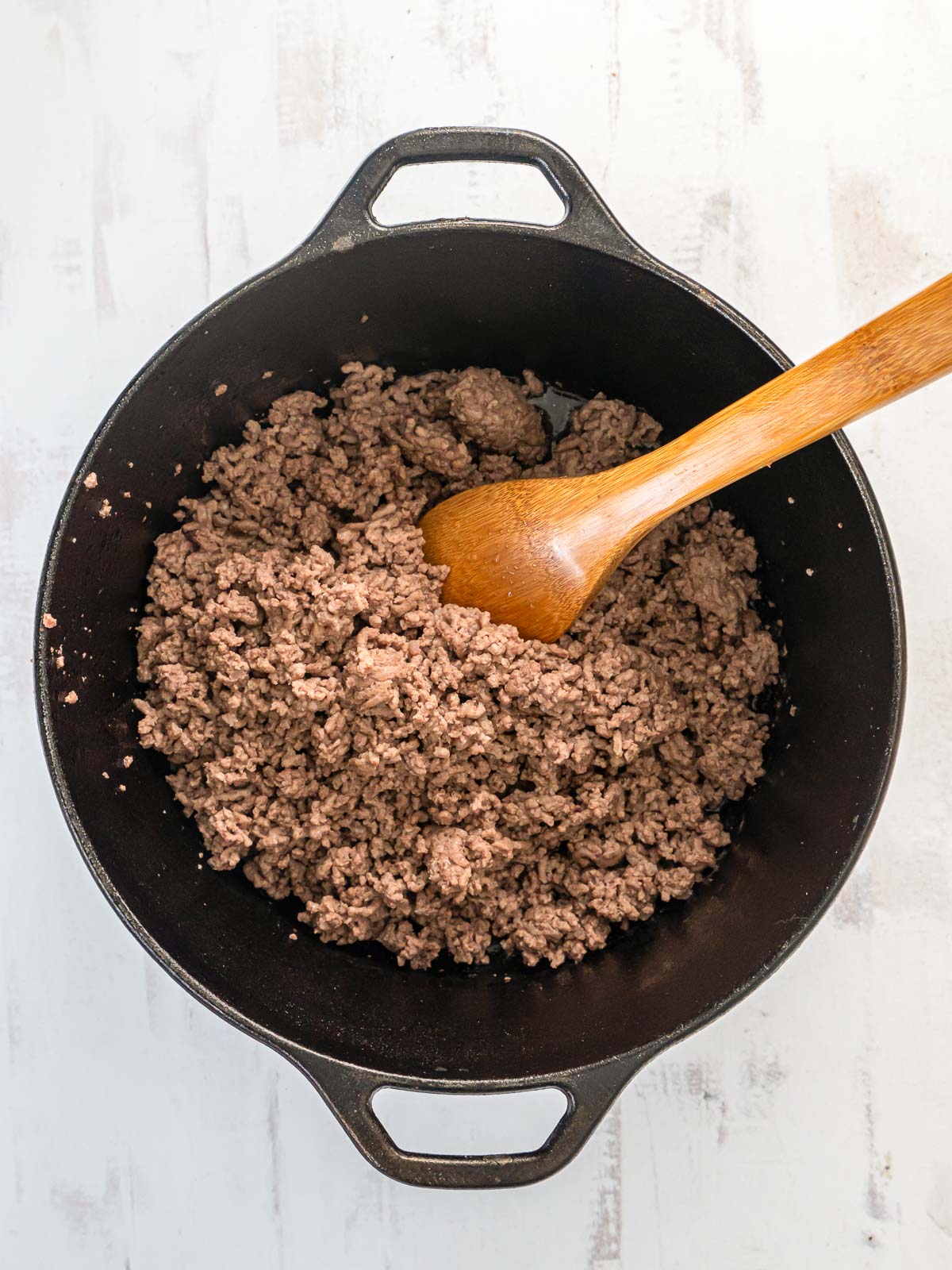 Ground beef cooking in a cast iron pot.
