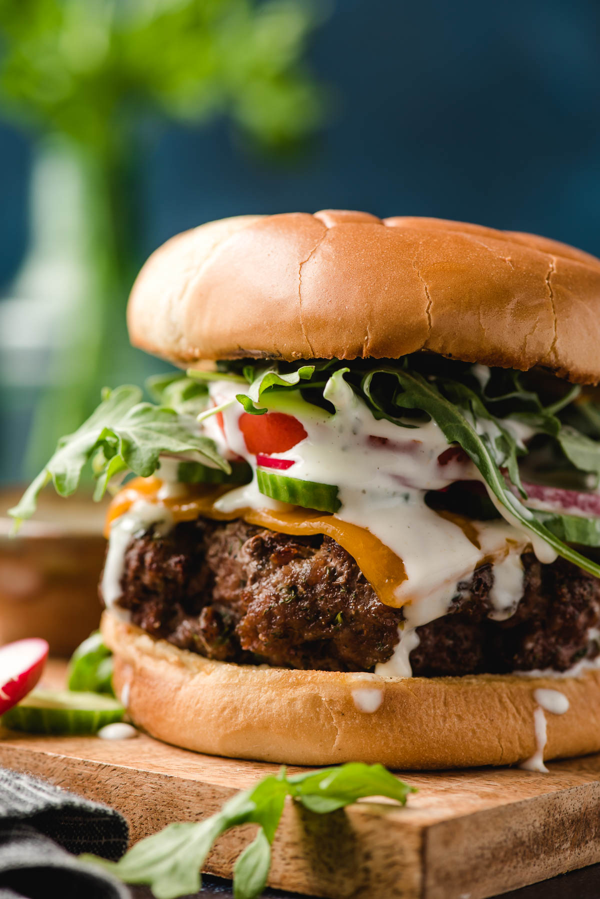 Ranch Dressing Burgers topped with cheese, tomato, and arugula shown on a brioche bun.