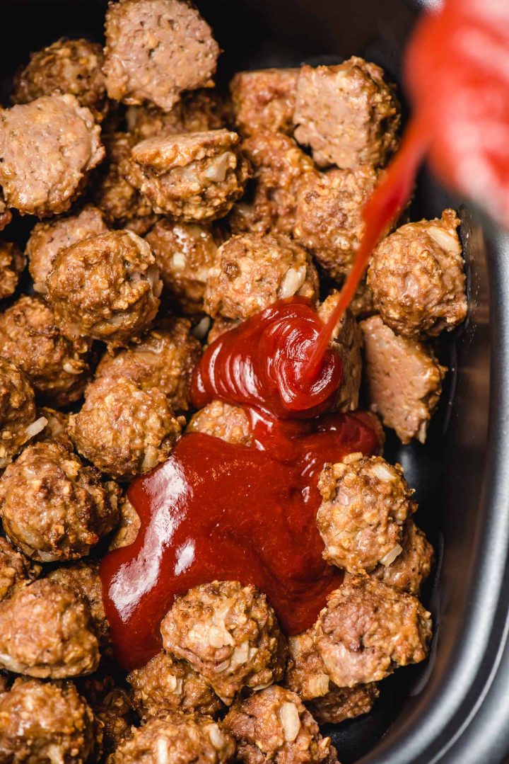 Homemade BBQ sauce being poured over meatballs in a crock pot.