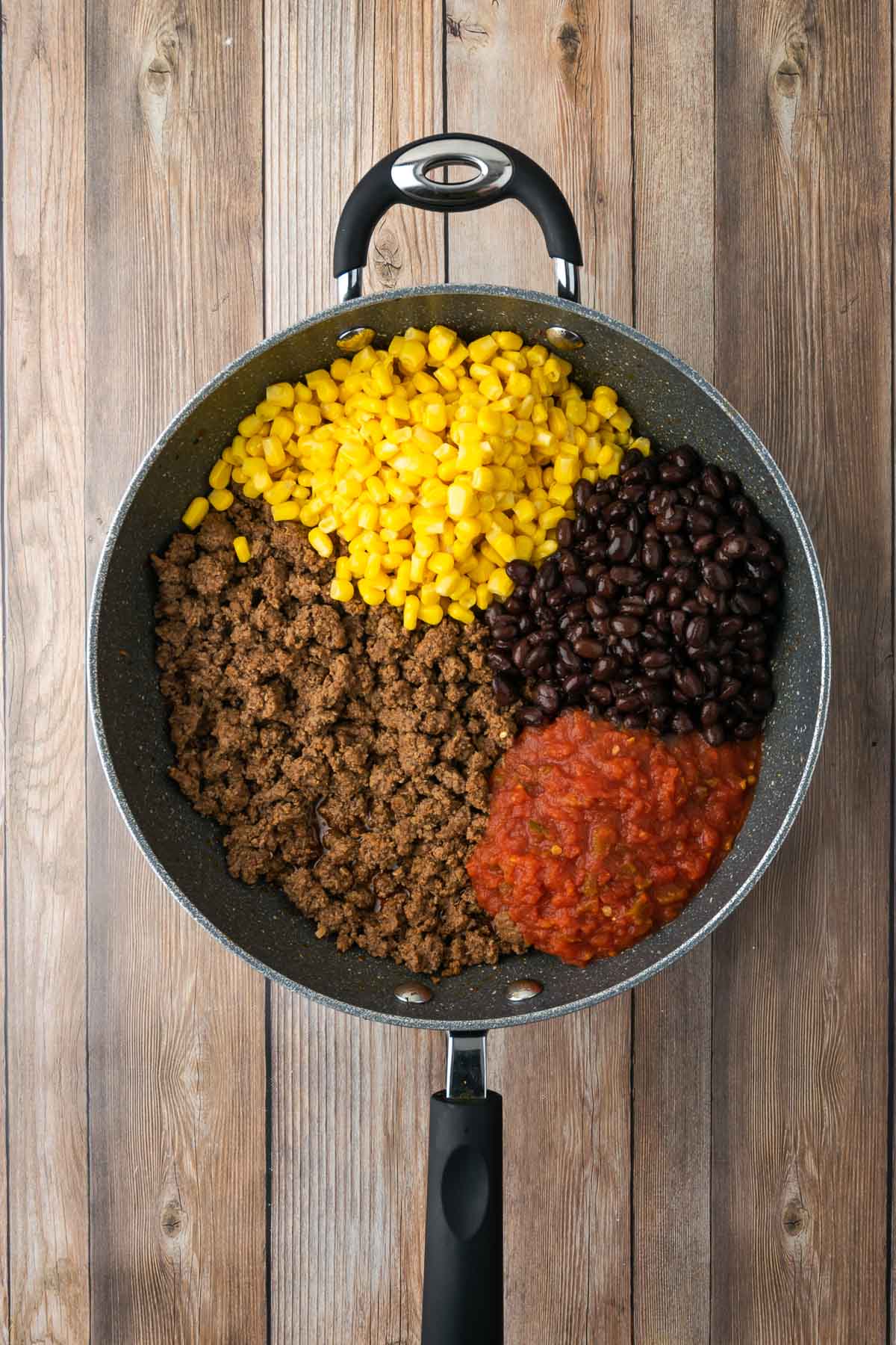 Skillet filled with cooked ground beef, corn, black beans, and salsa.