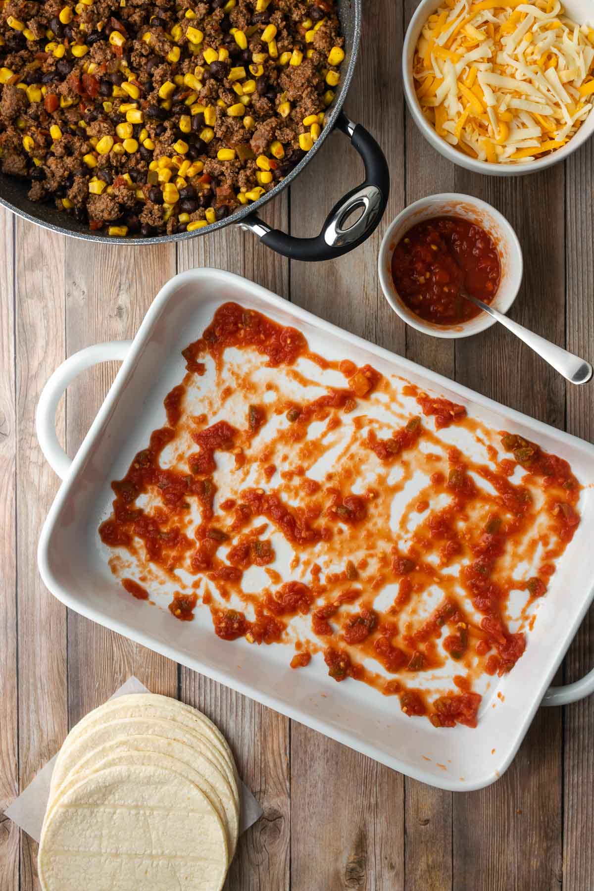 White casserole dish with salsa spread on the bottom.