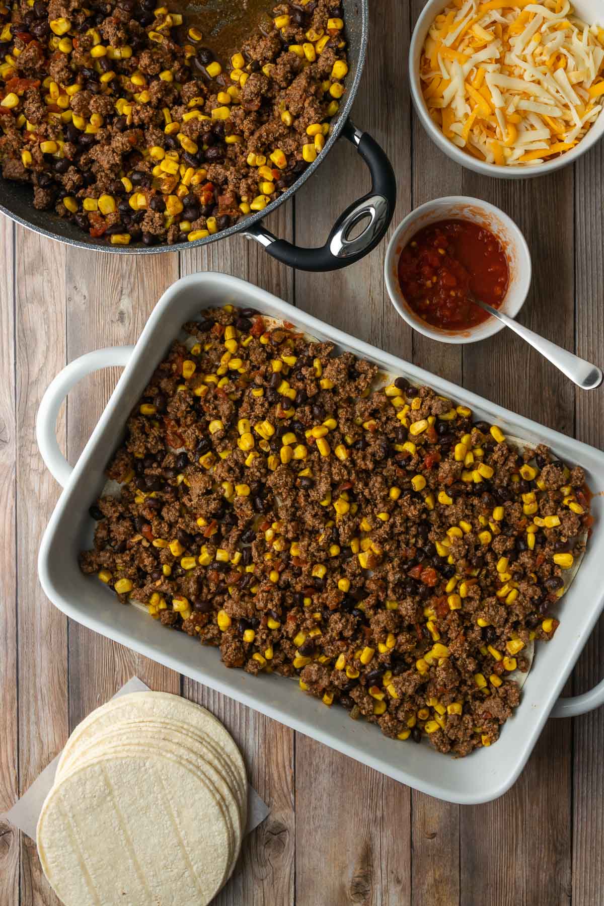 Casserole dish filled with salsa, corn tortillas, and ground beef mixture