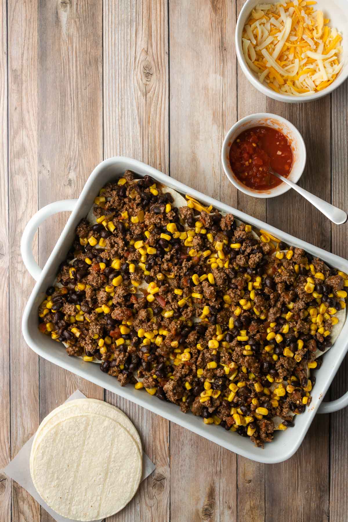 Casserole dish with layers of ground beef, salsa, tortillas, and cheese.