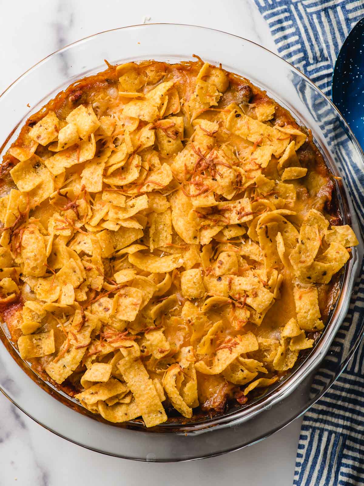 Round casserole dish filled with taco casserole and topped with Fritos.